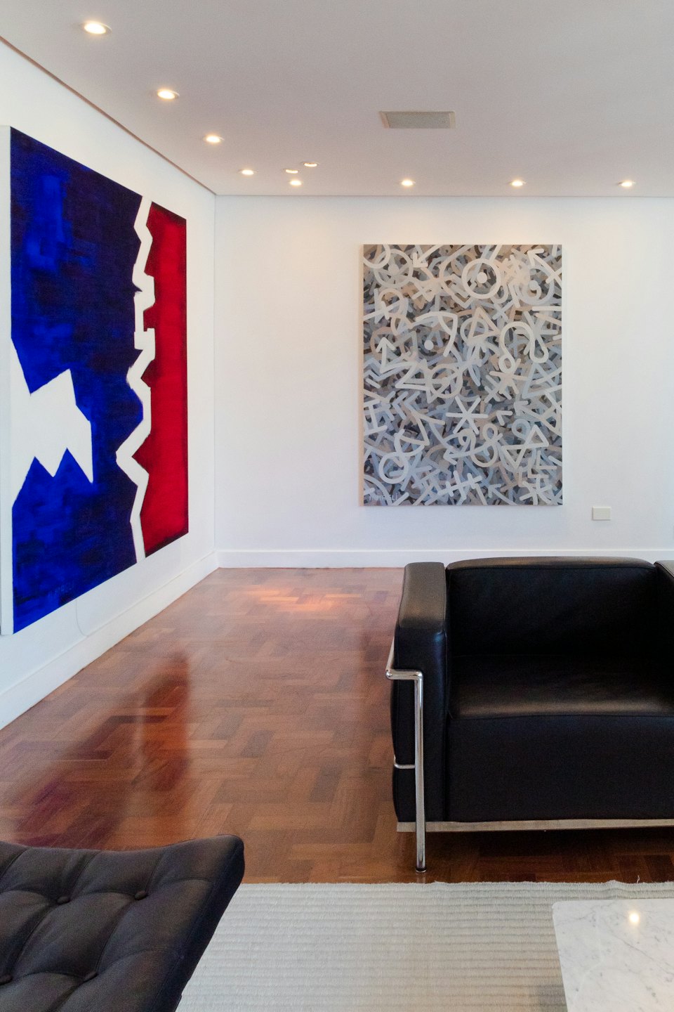 Abstract paintings in a modern room with leather armchairs.