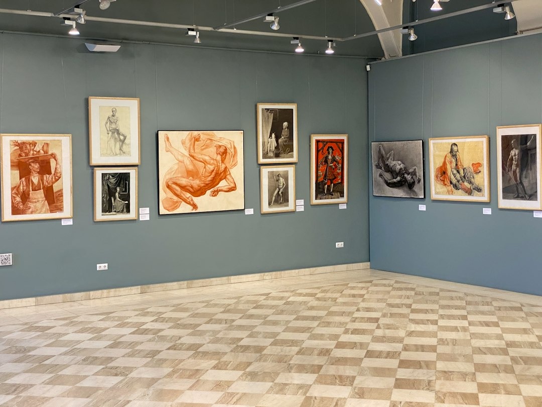 Framed charcoal and sanguine figure drawings hang on a gallery wall.