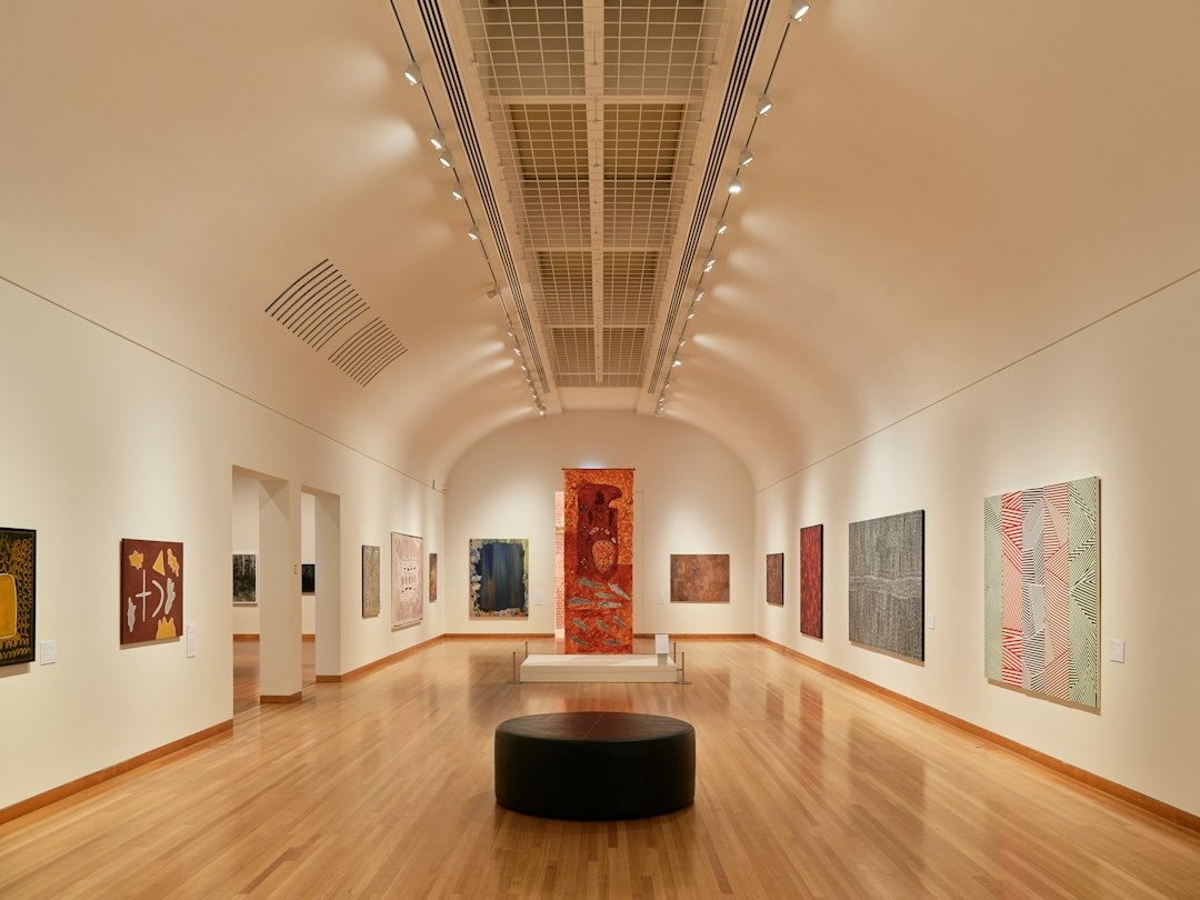 Art gallery hall with abstract paintings and a circular bench.