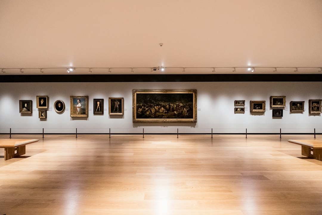Paintings hang in a row on a modern gallery wall.